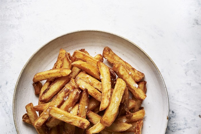 A white plate piled high with golden homemade chunky chips