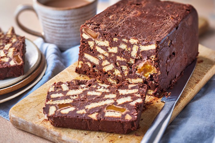 Chocolate biscuit cake on a board with a slice cut off