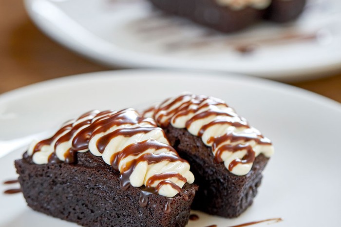 Two slices of iced chocolate stout cake with chocolate syrup on a plate