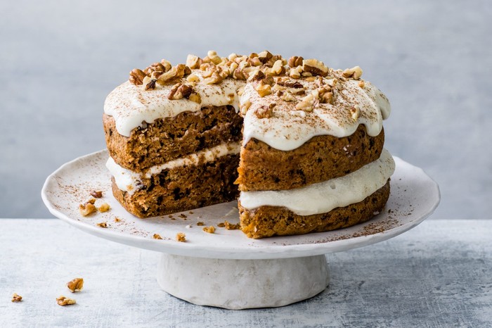 Easy Vegan Carrot Cake Recipe Vegan carrot cake topped with walnuts on a white cake stand