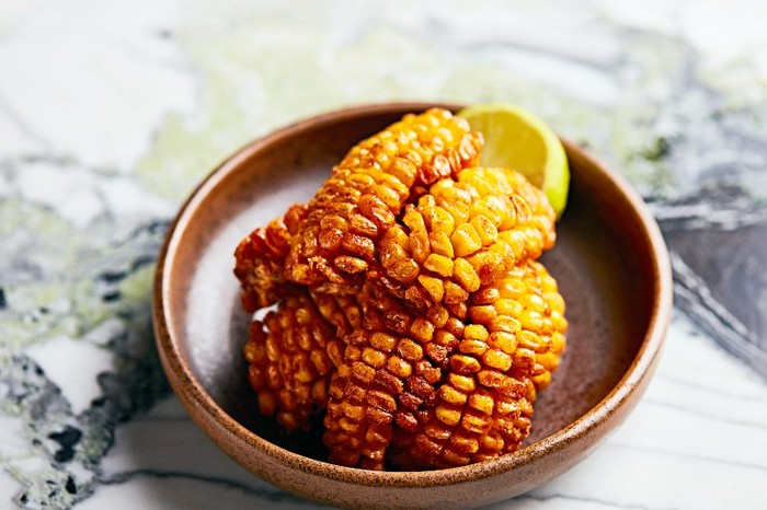 A round bowl of cooked corn ribs on a marble surface