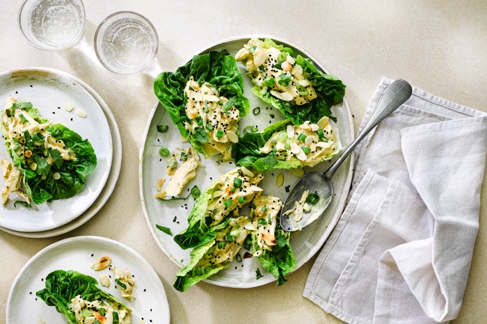 Little Gem lettuce leaves loaded with coronation chicken, presented on a platter with a silver serving spoon