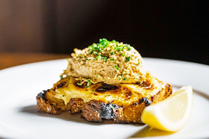 Welsh rarebit on toast topped with crab next to a lemon wedge