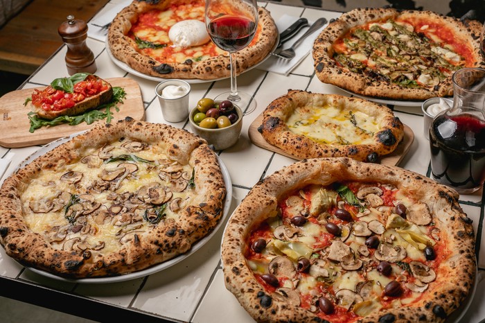 Four different sourdough pizzas with flatbread side and a jug of red wine