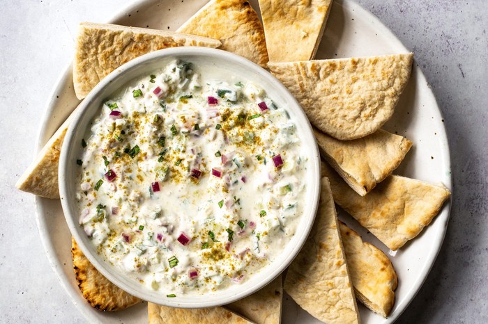 A small white bowl of dip with torn bread on the side