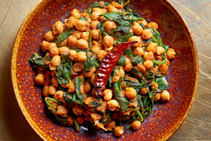 A chickpea curry with spinach and a red chilli on top