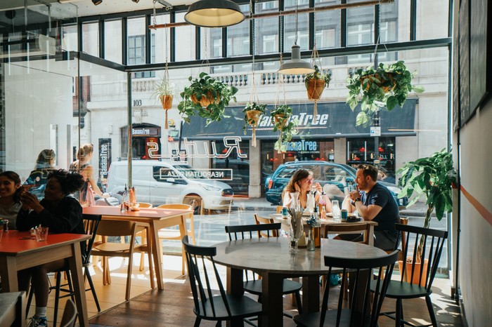 Rudy's interior featuring wooden chairs, hanging plates and floor to ceiling window