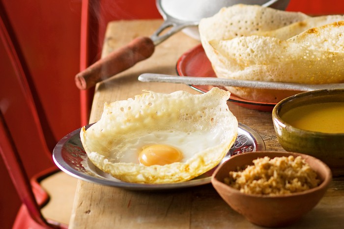 Egg Hoppers Recipe Egg hoppers with cooking pans in the background