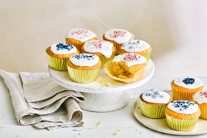 Vanilla fairy cakes with white icing displayed on a ceramic cake stand