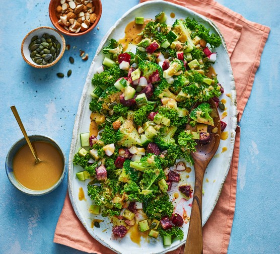 Platter of winter salad next to a ramekin of dressing