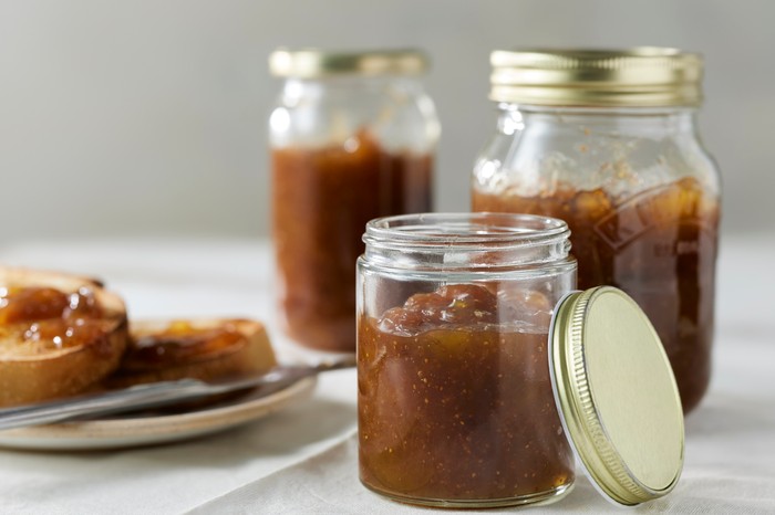 Three jars of fig jam with one jar with its lid off