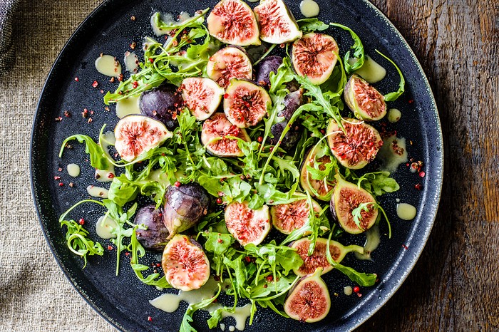 Halved figs and salad leaves on a plate