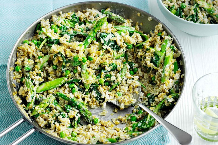 Risotto with freekeh and spring greens in a large silver pan with serving spoon