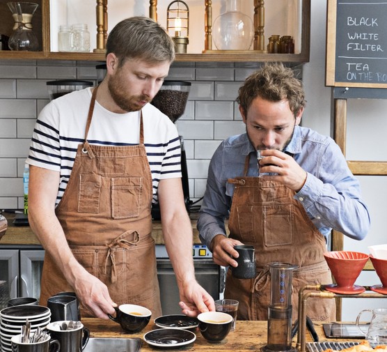 Two men making and tasting coffee in a kitchen