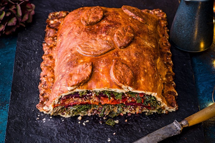 Giant vegan wellington on a board with the front cut off so you can see the filling