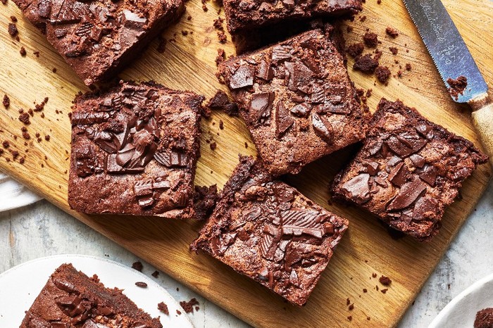 A wooden board topped with squares of chocolate brownie