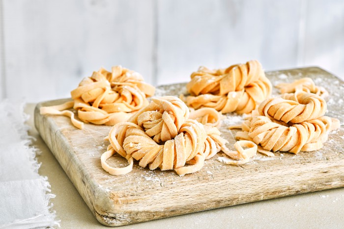 Nests of fresh linguine pasta on a wooden board