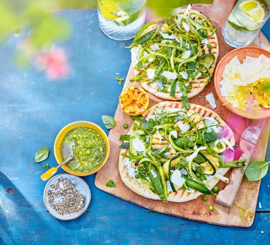 flatbreads spread with ricotta and topped with ricotta and green veg on a wooden board