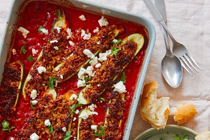 An oven dish of harissa lamb-stuffed courgettes in a red sauce