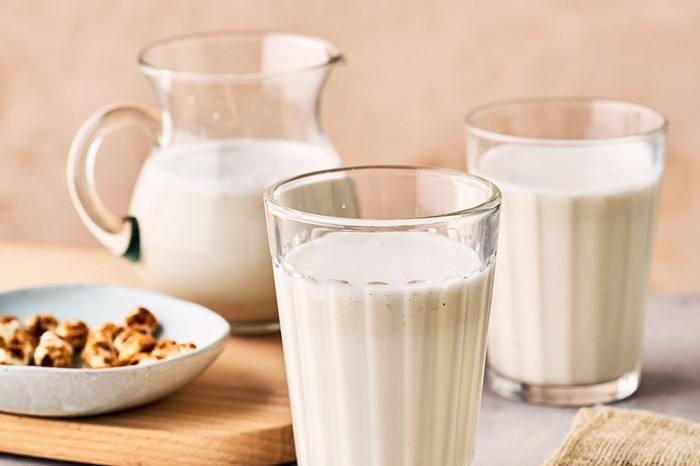 Two glasses and a jug of horchata next to a bowl of tiger nuts