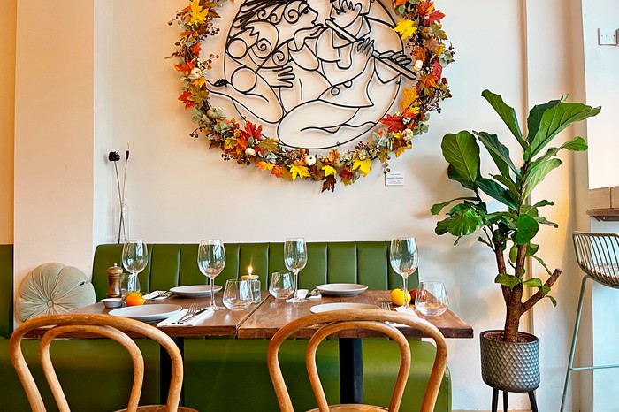 Harvest Interiors at Harvest, feautring green leather booths, tall plant pots and smart wooden chairs