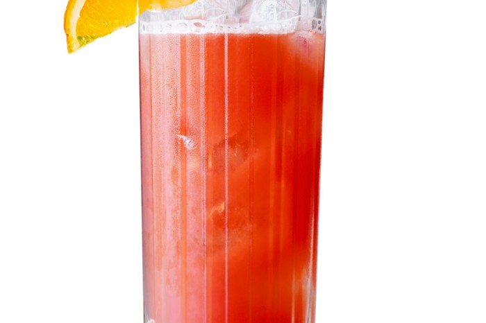 High glass filled with red liquid and wedge of orange on the rim