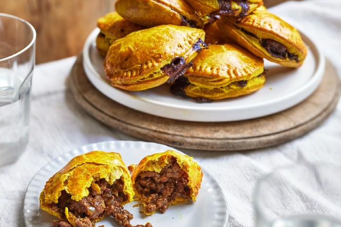 A plate of pastry patties filled with beef, with one broken open on a plate