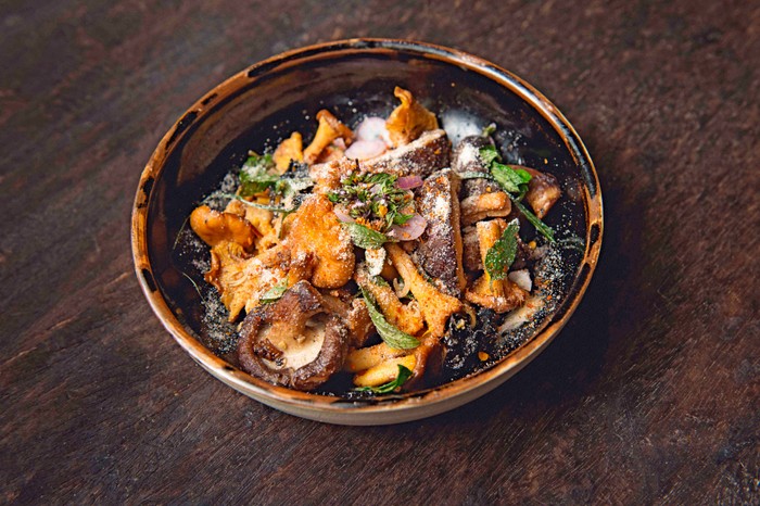 Small bowl of wild mushrooms with green leaves on top