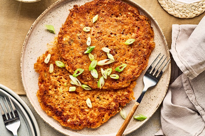 Two large kimchi pancakes on a plate sprinkled with spring onions