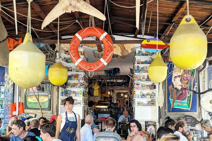 A busy restaurant with buoys hanging from ceiling