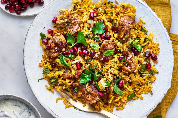 Plate of lamb biryani topped with pomegranate seeds and coriander leaves