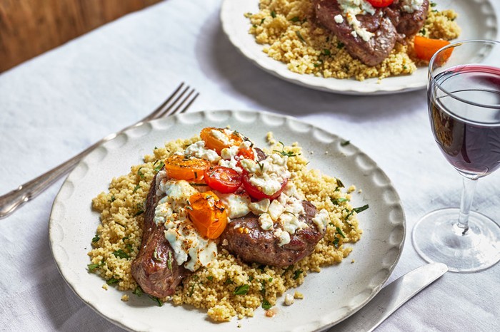 Lamb Steaks on a plate of couscous, plus another plate in the background