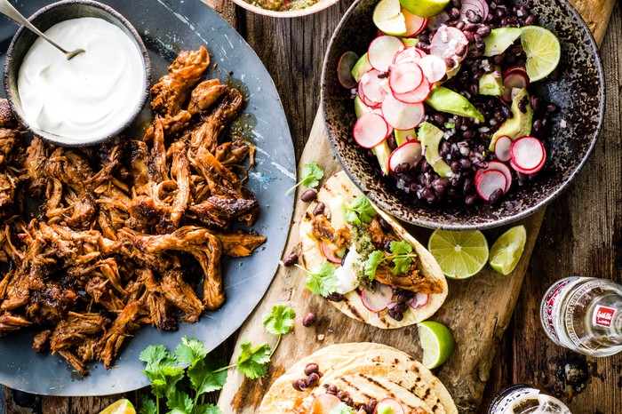 Braised lamb tacos on a wooden plank with with tomato salsa