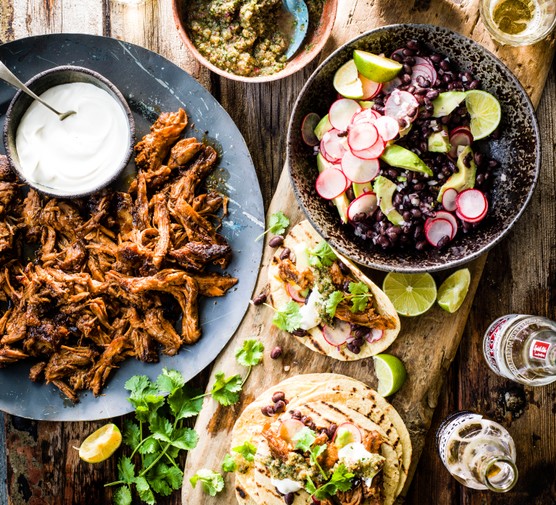 Braised lamb tacos on a wooden plank with with tomato salsa