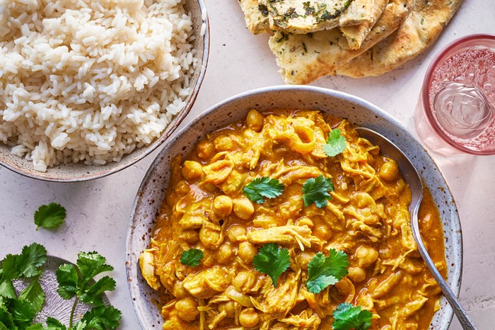 Leftover turkey curry in a bowl next to rice and naans