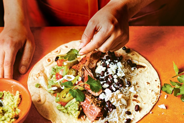 Open tortilla loaded with steak strips, guacamole and salad