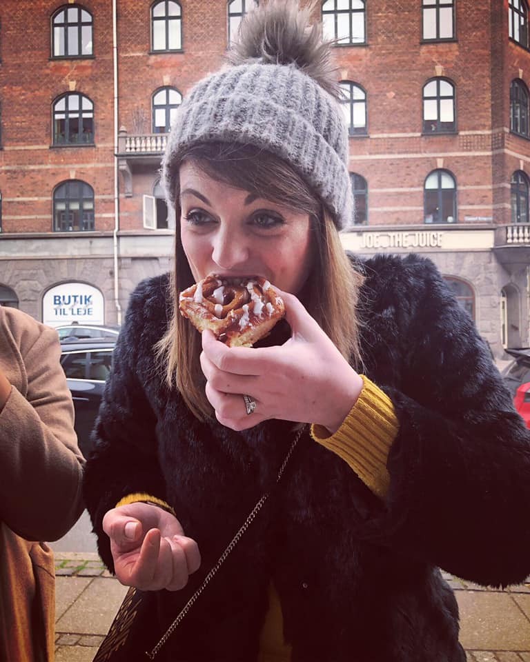 Linzi Pucino profile image eating a bun wearing a grey bobble hat