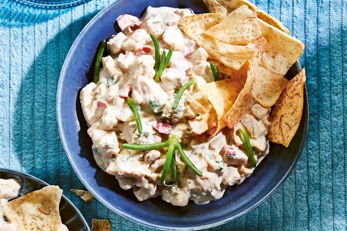 A blue bowl filled with ceviche with tortilla crisps on the side