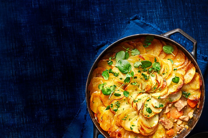 A lamb hotpot in a casserole dish with fresh herbs