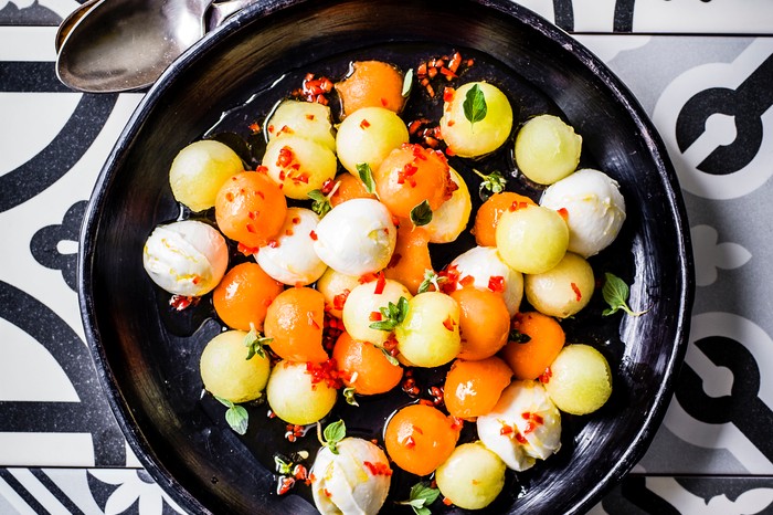 Colourful melon and mozzarella balls in a black salad bowl