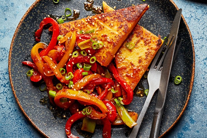 Polenta cut into triangles with side of peppers topped with spring onions