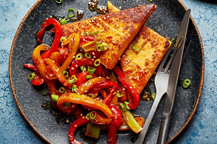 Miso polenta with soy peppers Polenta cut into triangles with side of peppers topped with spring onions