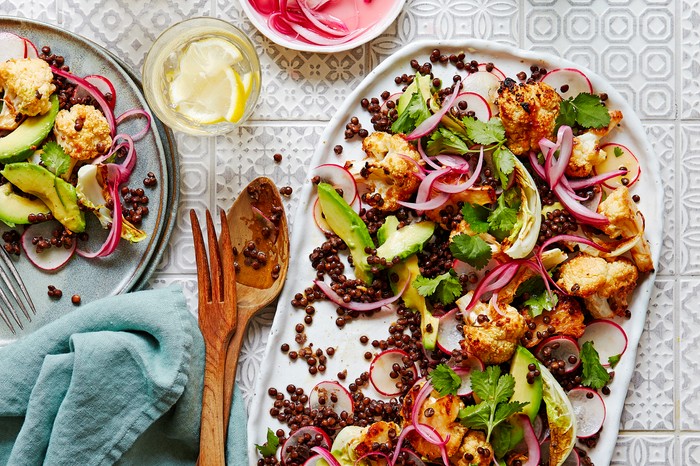 A platter topped with roasted cauliflower, lentils and slices of avocado