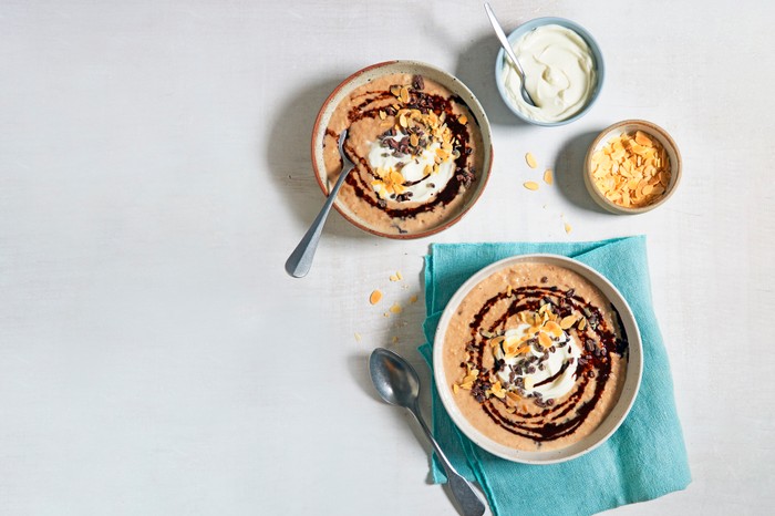 Two bowls of porridge with toppers on the side