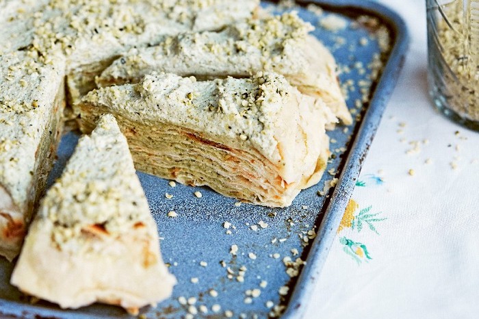 Moldavian layered pie on a silver tray on top of a white patterned tablecloth