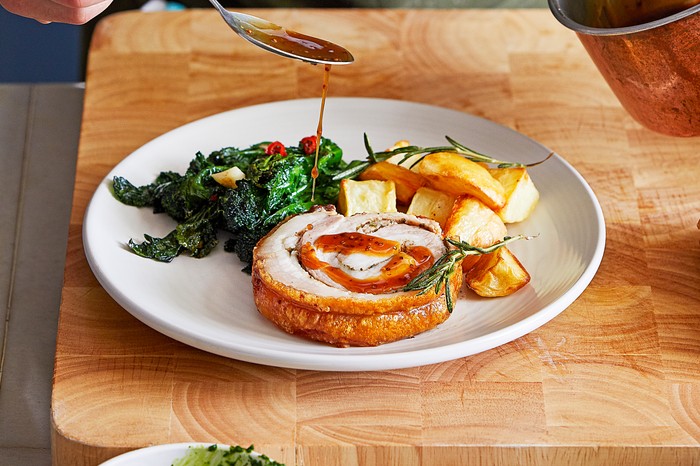 Porchetta with salsa verde, purple sprouting broccoli and roast potatoes A plate of Sunday lunch with roast pork belly and potatoes