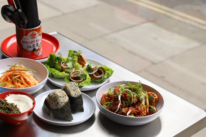 A selection of small plates and chicken dishes on an table outdoors