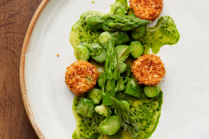 Asparagus and Goat's Cheese Recipe served on a round white plate on a dark brown wooden table