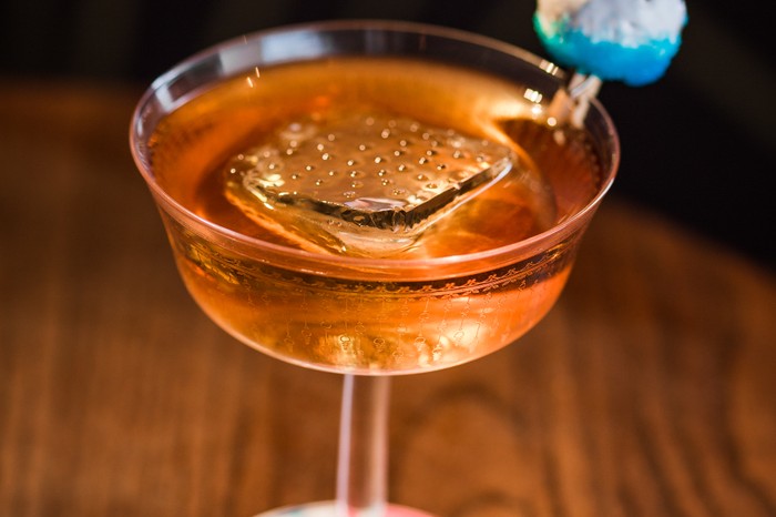 A sophisticated coupe cocktail with a large ice cube in the middle