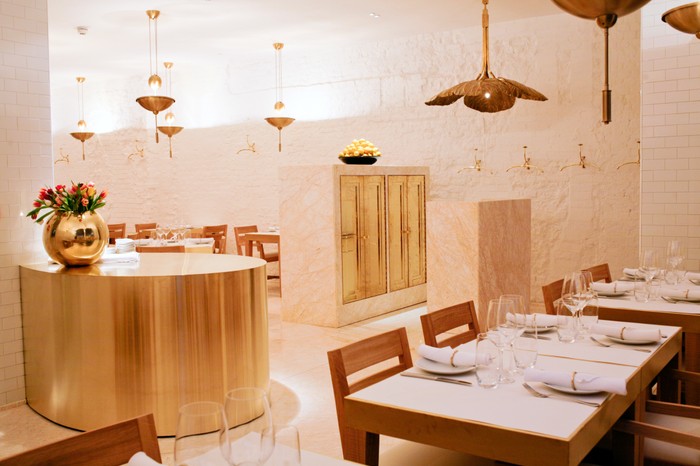 NOPI restaurant interiors with white washed walls, copper lights and wooden chairs round a marble topped table